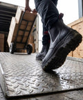 Person wearing Men Slip On Work Boots With Composite Toe Lightweight Tough As Nails Water Resistant Electric Hazard Safe Anti Static Insulated Fire Station Mechanic Boots For All Day Comfort On The Job carrying boxes on a ramp