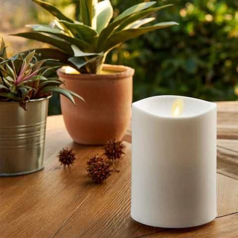 Outdoor Flameless LED Ivory Candle With Real Moving Flame And Melted Edge 3.75 Inch By 5 Inch Battery Operated Timer on a patio table