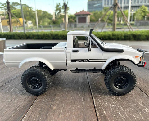 Rugged One Sixteenth Scale RC Rock Crawler Truck 4x4 With Realistic Interior on wood surface, side view, all terrain ready