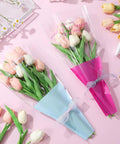 Wrapped tulip bouquets in Disposable OPP Flower Sleeve Bags for Bouquets 150 Pack Clear Floral Packaging Wrap for Flowers DIY Gift Wrapping Supplies See Through Protective Sleeves No Fuss Easy Wrap on a pink background