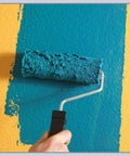 Hand rolling teal paint over yellow wall with textured roller