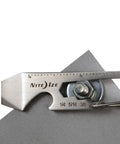 Silver Carabiner Key Clip One And Eleven Sixteenth Inch close-up with ruler markings and bolt holder on metal surface