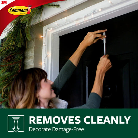 Person using Damage Free Outdoor Wall Hooks Kit With Weather Resistant Strips on a black door to hang decor