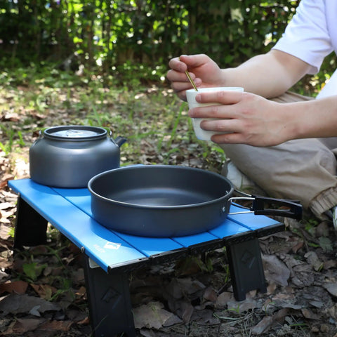 Ultralight Folding Beach Table For Camping And Picnics Portable Aluminum Side Table with cookware outdoors in a park setting.
