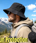 Man wearing Packable Sun Bucket Hat For Men With UV Protection Lightweight Waterproof Outdoor Cap For Hiking Beach And Travel Breathable Black Sun Hat Foldable Design For Easy Packing And All Day Comfort with mountains in the background