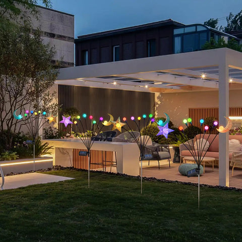 Colorful solar pathway lights with star and moon shapes illuminating a modern patio garden at dusk.