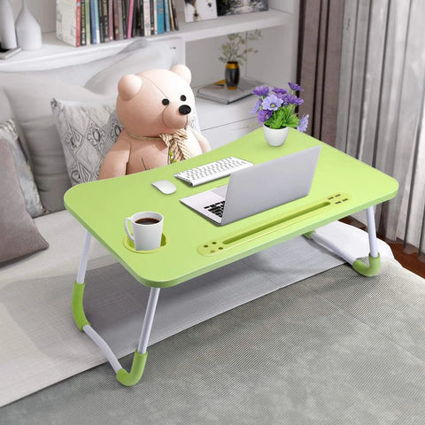 Green foldable laptop desk bed table with cup holder on a bed, featuring a laptop and teddy bear next to a window.