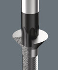 Close-up of a drill bit penetrating solid metal, showing cutting edges and spiral grooves on a grey background.