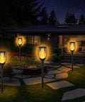 Four 7 Pack Solar Torch Lights With Flickering Flame For Realistic Look illuminating a garden pathway at night.