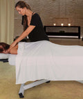 Massage therapist using EarthLite Ellora Electric Lift Massage Table With Flat Top And Black Finish for client treatment.