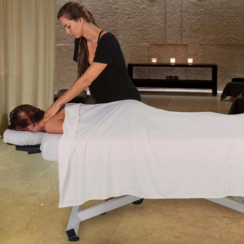 Massage therapist using EarthLite Ellora Electric Lift Massage Table With Flat Top And Black Finish for client treatment.