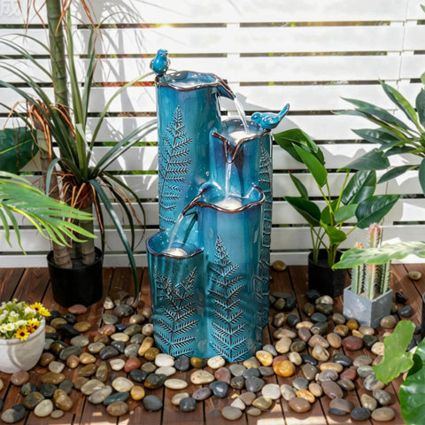 Totally Dope 32 Inch Tall Ceramic Outdoor Water Fountain With Led 4 Tier Tropical Cascading Waterfall Turquoise Glaze Embossed Fern Pattern Bird Attracting Garden Yard Patio Decor on a wooden deck with plants.