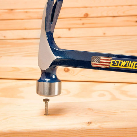 Big Blue Framing Hammer 25 Oz Pro Grade USA Made with straight rip claw and shock reduction grip driving a nail into wood