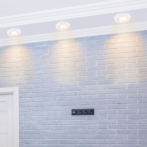 Pack Of 10 Flush Mount MR16 Spotlight Fixtures With Swivel Bracket in ceiling, illuminating a grey brick wall, matte white finish.