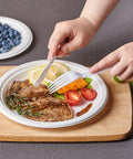 Heavy Duty 9 Inch Disposable Party Plates 150 Pack Eco Friendly Biodegradable Sugarcane Bagasse White Unbleached Dinner Plates For BBQs Picnics And Parties Compostable No Plastic used for serving a meal with steak and vegetables.