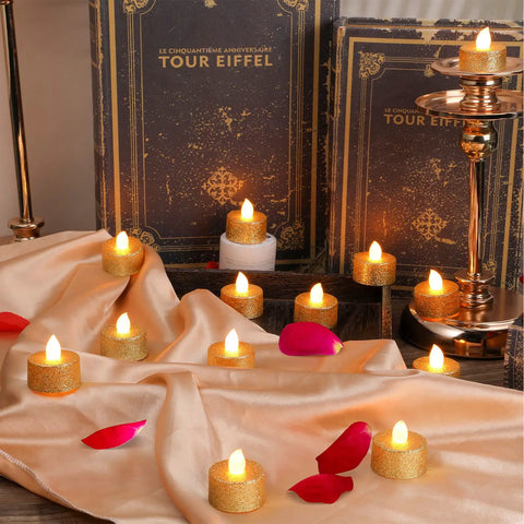 Gold LED Tea Lights Flameless Battery Operated Tealights 24 Pack For Holiday Decor Weddings Parties Birthday Home Ambience Glitter Votive Candles With Easy Cleanup And Safe Realistic Long Lasting Lit Glow arranged on cloth with petals and books.