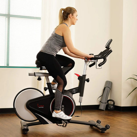 Smooth Riding Indoor Cycling Bike Featuring Forty Pound Rear Flywheel And Digital Console To Dominate Your Daily Grind And Ride With Silent Magnetic Resistance Upgrading Your Whole Home Gym Setup in use by a rider.