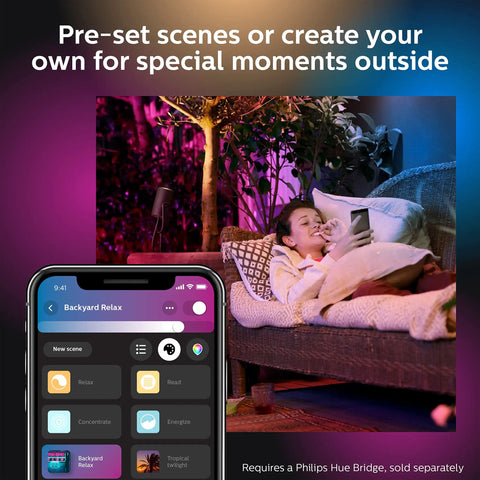 Child relaxing on outdoor sofa with app controlling Lily Outdoor Smart Spotlight Base Kit Three Pack With White And Color Ambiance LED Walkway Lights For Low Voltage Landscape Lighting No Fuss Setup Bridge Required Control With App And Voice Weatherproof.