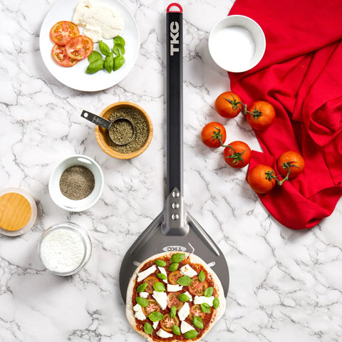 8 Inch Perforated Pizza Peel With Long Handle Aluminum Turning Peel beside pizza ingredients on marble surface