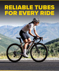 Cyclist riding a bike with mountains in the background, promoting 2 Pack 700C Bike Inner Tubes With 48mm Presta Valve, Butyl Rubber.