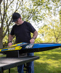 Man adjusting Sonicwake RC Boat 48 Inch Self Righting Brushless 8S Ready To Run in park setting on a table