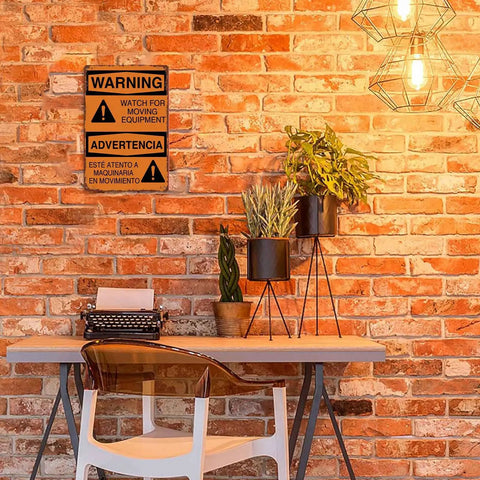 Warning Moving Equipment Metal Sign 8x12 Inch Aluminum Wall Decor on brick wall above desk with plants and vintage typewriter.