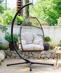 Cozy Outdoor Hanging Egg Chair with Stand and UV Resistant Cushion in a garden setting, showcasing durable steel frame and adjustable cushion.