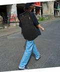 Person walking on street with Heavy Duty Black Drum Bag Made For Open Road Rhythms slung over their shoulder.
