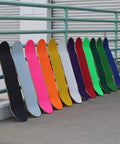 Row of skateboards with colorful decks including the 9 By 33 Inch Grip Tape Sheet For Skateboards Cruisers And Scooters Black 80 Grit