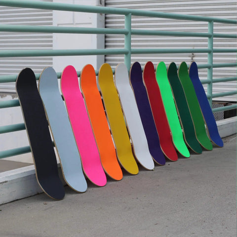 Row of skateboards with colorful decks including the 9 By 33 Inch Grip Tape Sheet For Skateboards Cruisers And Scooters Black 80 Grit