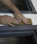 Hands using Extra Large Drywall Sanding Sponge With Fine And Medium Grits For Rough And Finish Sanding on painted surface edge