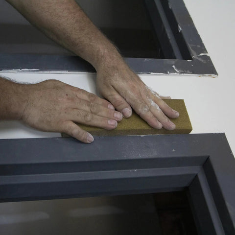 Hands using Extra Large Drywall Sanding Sponge With Fine And Medium Grits For Rough And Finish Sanding on painted surface edge