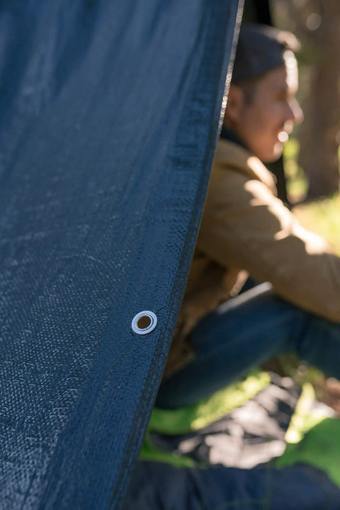 Side view of Medium Duty Ripstop Camping Tarp 6 By 8 Feet Waterproof Cover Dark Green 5 Mil Thick With Reinforced Grommets providing shelter.