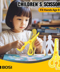 Child using yellow children's scissors for crafts on a table, fit for ages 8+, with paper cutouts visible.