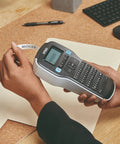 Badass Portable Label Maker Featuring Authentic Qwerty Keyboard And Rapid Response Touch Keys in use printing "INVOICES" label