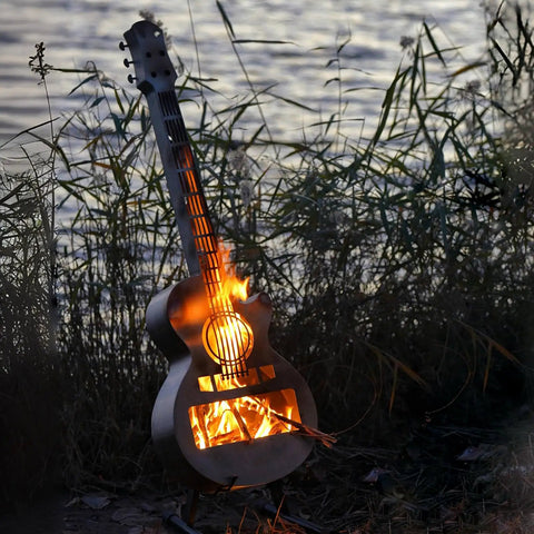Guitar Shaped Outdoor Fire Pit Stainless Steel Wood Burning With Removable Ash Pan, lit at twilight by lakeside.