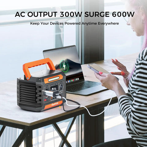 Portable Power Station 230Wh With 300W Continuous Power And 600W Peak next to laptop and phone charging on desk