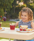 Child enjoying a meal at a Six Seat Kids Picnic Table with Umbrella, showcasing outdoor use with snacks and drinks, multi-color design.