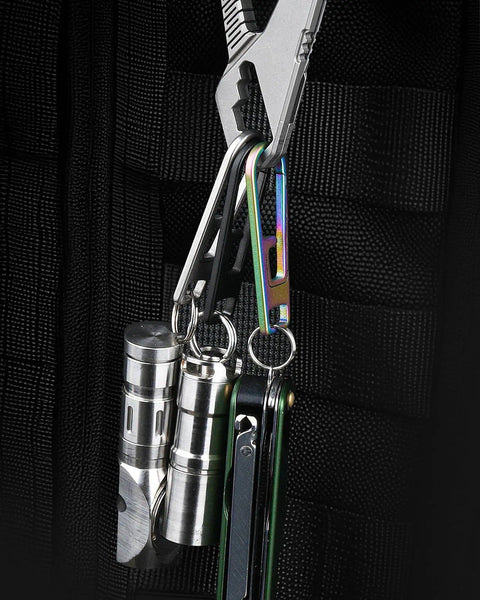 Beefed Up Heavy Duty Titanium Zipper Pull Replacement Kit attached to black fabric showing multiple metallic tools and accessories