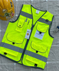High Visibility Safety Vest For Men And Women With 9 Pockets, Reflective Strips For 360 Degree Night Visibility, ANSI ISEA Approved Work Vest In Yellow, X Large on a table with helmet and pliers