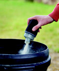 Hand holding a dusting tool above a black bucket, releasing fine powder for woodworking, showcasing the Quarter Sheet Orbital Palm Sander Professional Grade 220 Watt Motor Featuring A Snappy Pressure Trigger Switch Lightweight Orange Body Crushes Tough Woodwork Jobs Quickly To Leave Surfaces Smooth As Silk Daily.