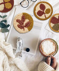 Six Piece Punch Needle Coaster Kit Set For Beginners And Adults, DIY Embroidery Craft with patterns and yarns on cozy table