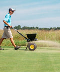 Person using Spyker All Season Spreader Kit Ergo Pro 50 Pound Broadcast Spreader With 25 Pound Bag Spreader on lawn