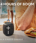 Wonderboom 4 Portable Bluetooth Speaker With Waterproof Floating Design on table near sandwich, 14h playtime display