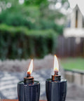 Glass Table Torch Set For Outdoor Patio Vibe, Herringbone Blue 3-Pack lit on patio table with green background