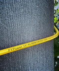 Badass 1/4 Inch By 100 Feet Air Compressor Hose Crafted From Tough Reinforced Polyurethane, coiled around a textured wall.