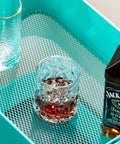 Close-up of Three Tier Mesh Rolling Cart On Wheels With Handle Turquoise Finish showing mesh surface with beverage items.