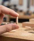 Person holding a Fluted Wooden Dowel Pins Set Natural Hardwood Dowels One Quarter Inch By One And One Fifth Inch Beveled Ends.