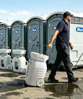 No Sweat 12 Gallon Heavy Duty Portable Hand Washing Station being pulled beside portable restrooms at an outdoor event.