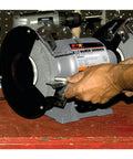 Heavy Duty 8 Inch Bench Grinder With A 0.75 HP Motor, Cast Iron Housing, ball bearings, being adjusted on workbench